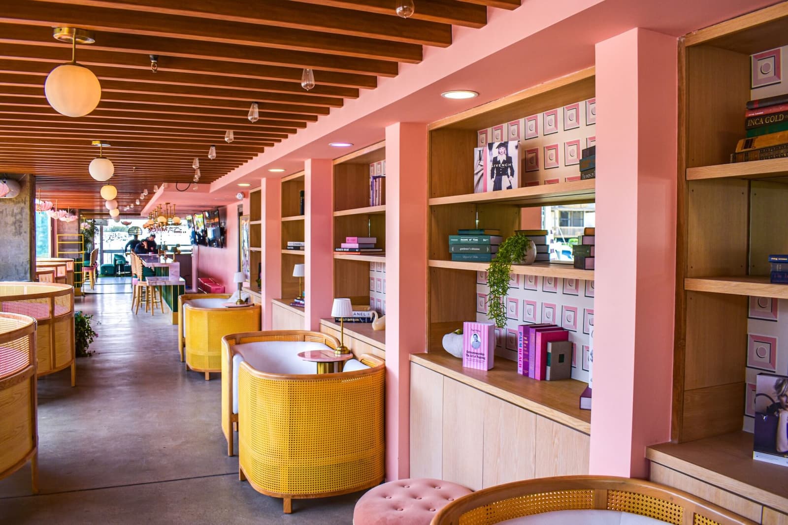 The pink library corridor of book-lined shelves and cane tub chairs