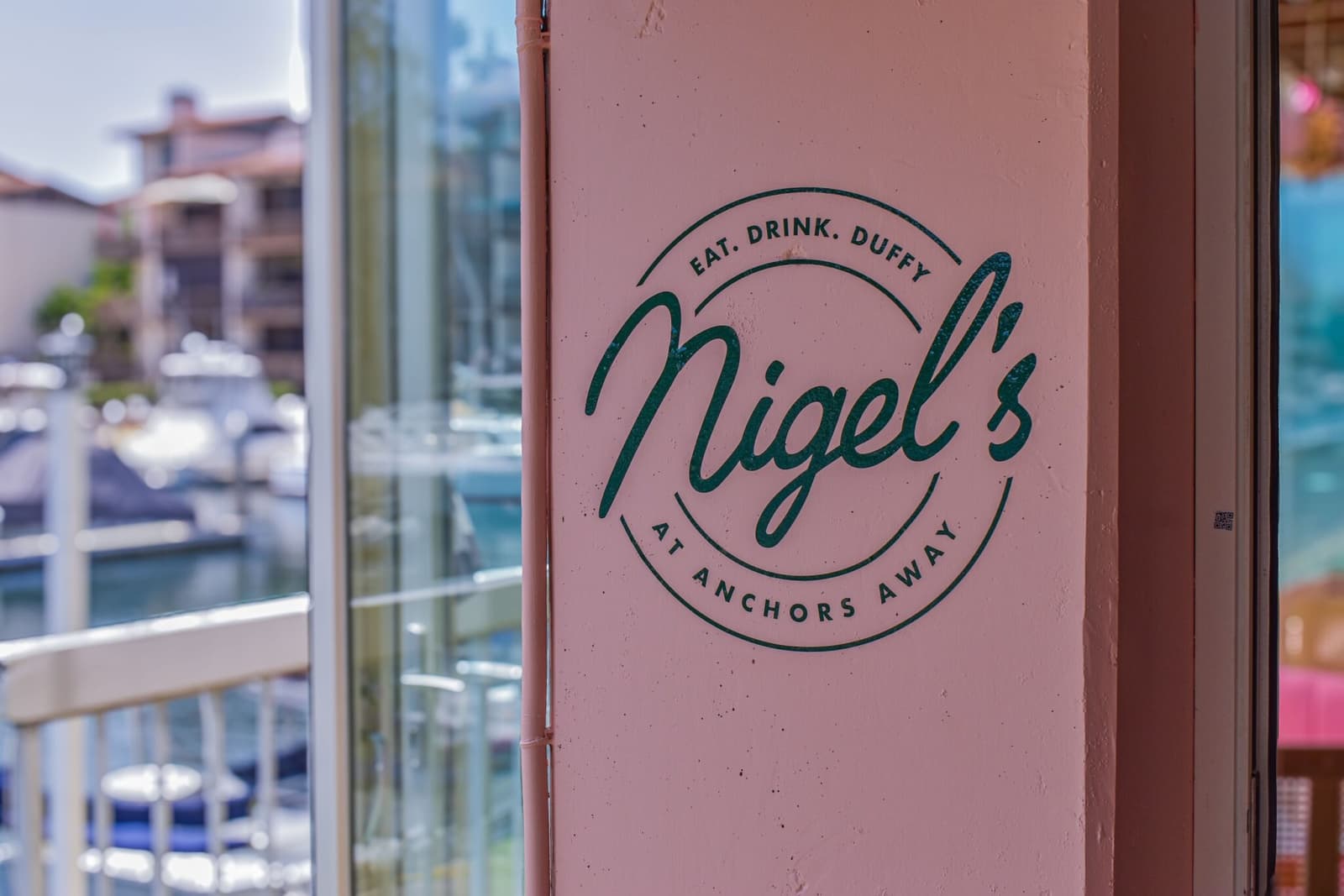 The Nigel's at Anchors Away seal on a pink pillar above the marina