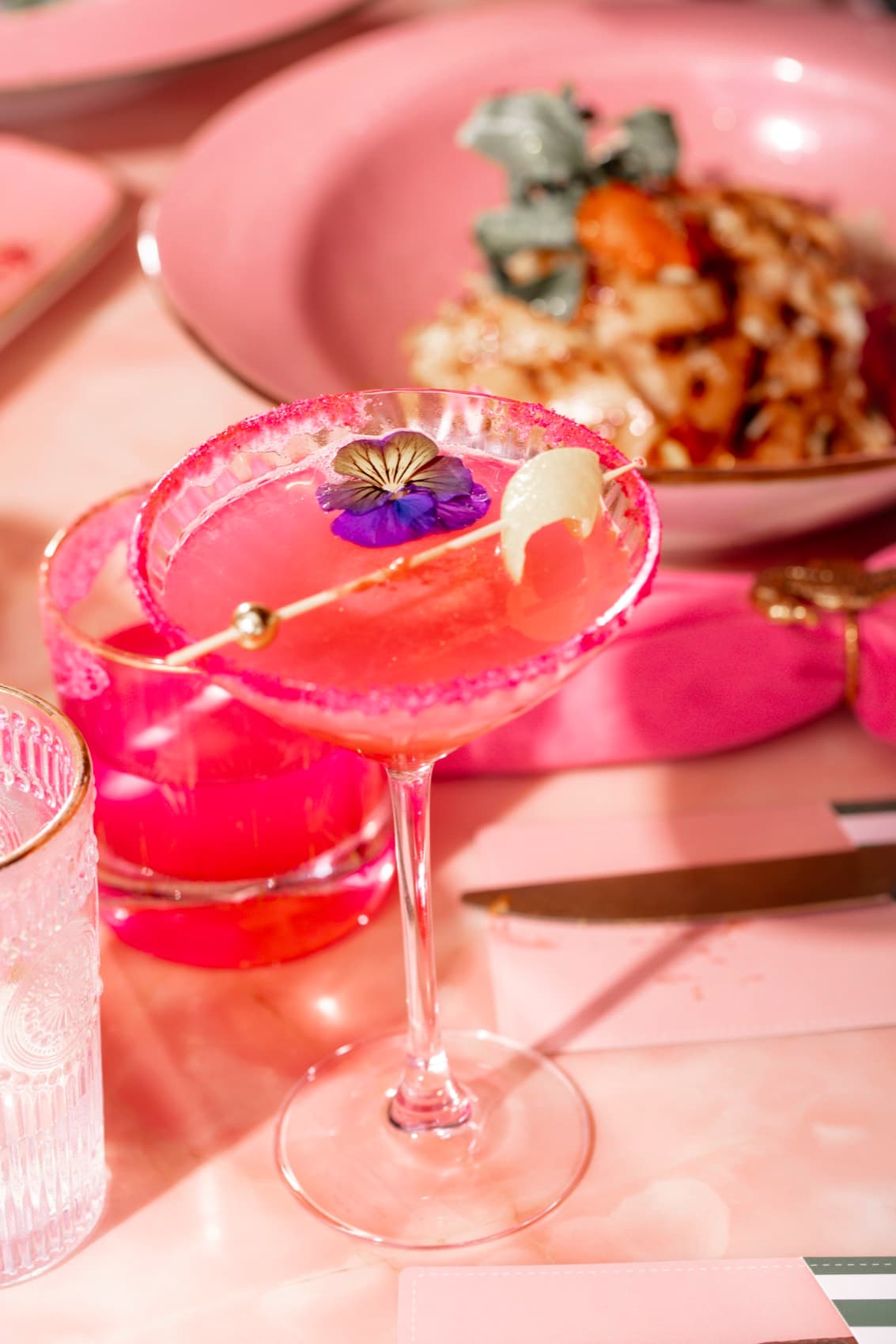 A hot-pink coupe cocktail with edible flowers at Nigel's