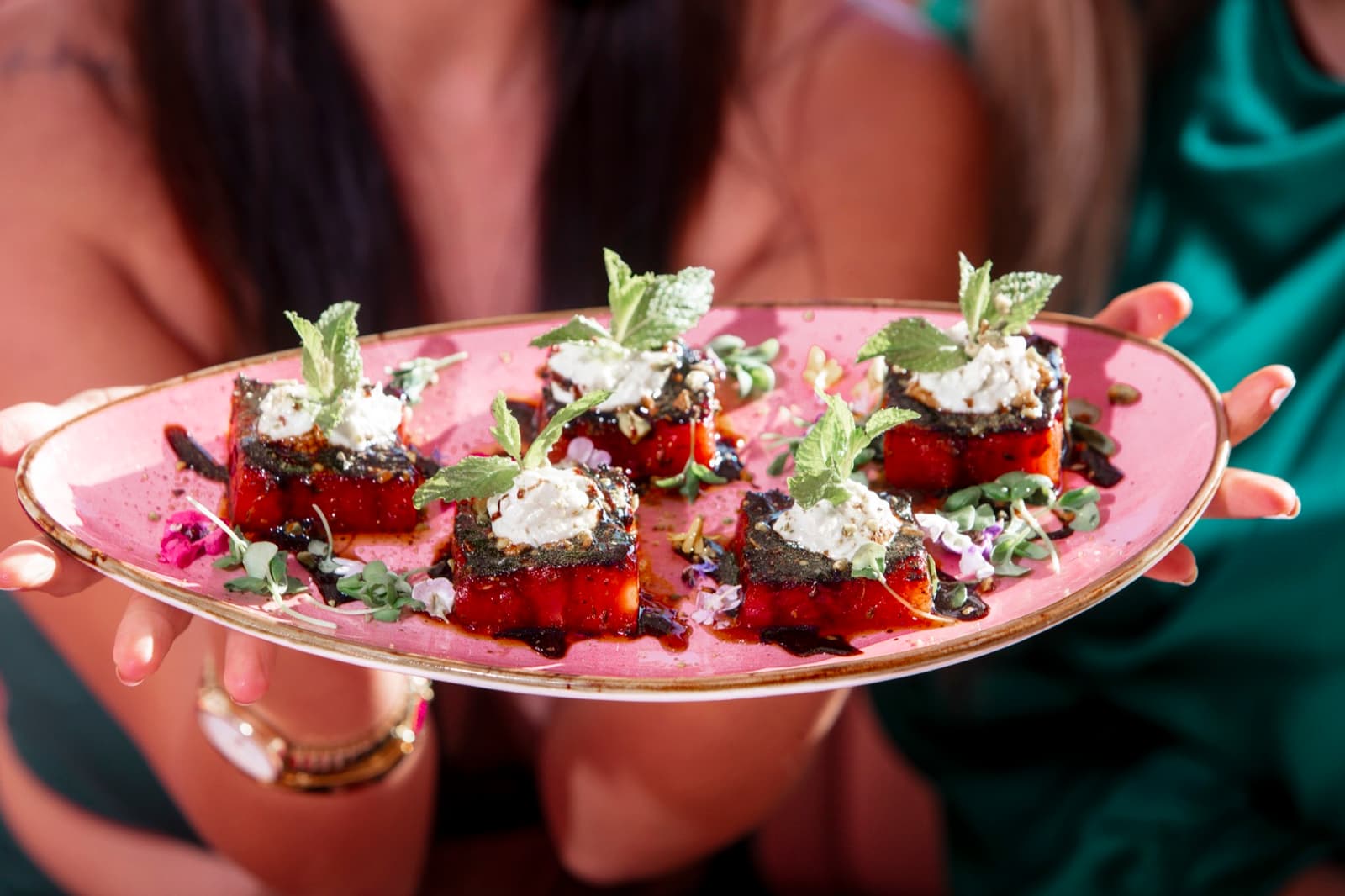 Seared watermelon with feta plated on pink at Nigel's