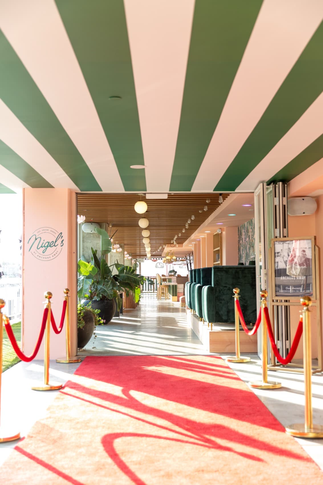 A red carpet entrance beneath candy-stripe ceilings at Nigel's