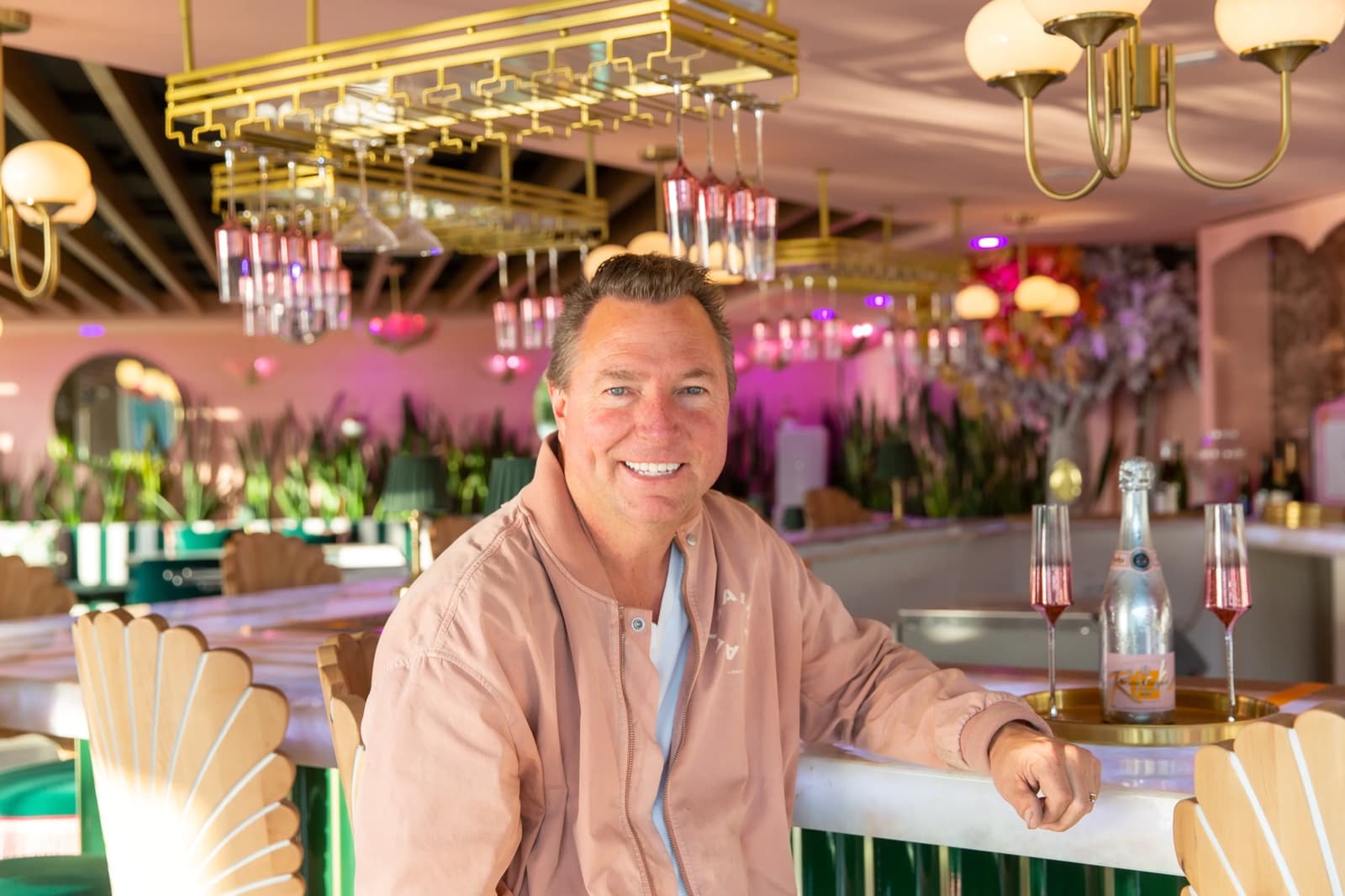 Nigel, owner of Nigel's Waterfront Restaurant, in the pink dining room with champagne